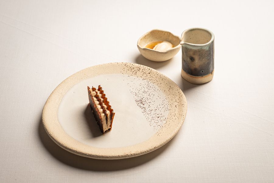 Un milhojas sobre plato moteado, con su jarrita al lado