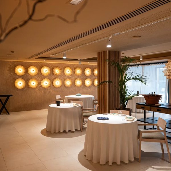 La sala con las mesas vestidas y la pared de apliques encendida