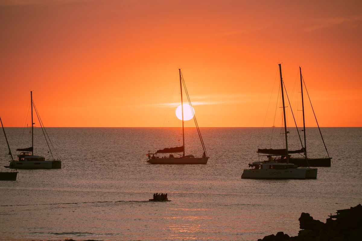 El sol entrando en el mar frente a Cala Saona, con los veleros fondeados en silueta