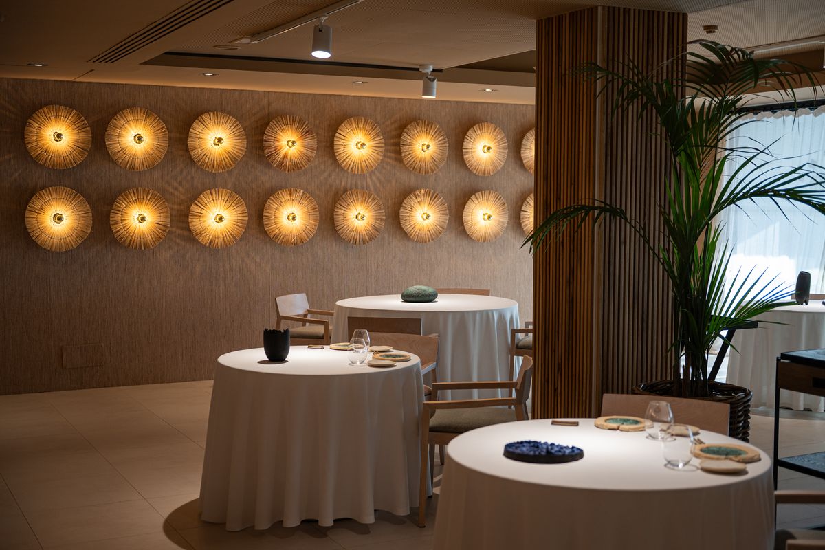 La sala de Sol Post de noche, con la pared de erizos de luz encendida sobre las mesas vestidas